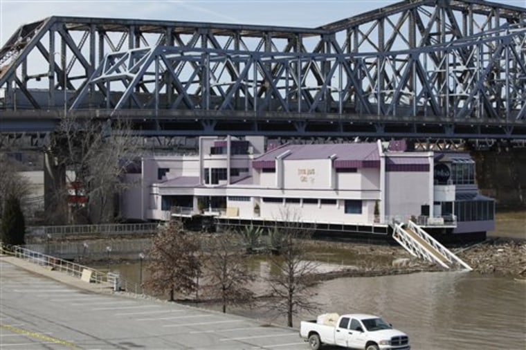 The Waterfront restaurant is held by a tugboat, March 12,  in Covington, Ky. The Waterfront, a floating restaurant, broke free from its dockside mooring on the rain-swollen Ohio River, and drifted about 85 to 100 yards downriver to a towering bridge nearby but a rear mooring line held it firmly as 83 nervous dinner patrons awaited rescue.
